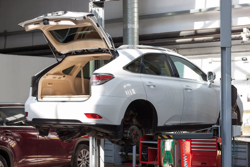 a white car being lifted in a garage for repair 